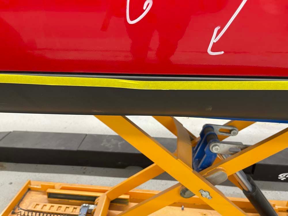 A red car is sitting on a yellow scissor lift