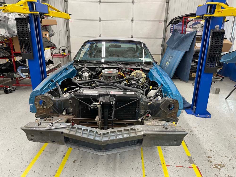 A blue car is sitting on a lift in a garage.