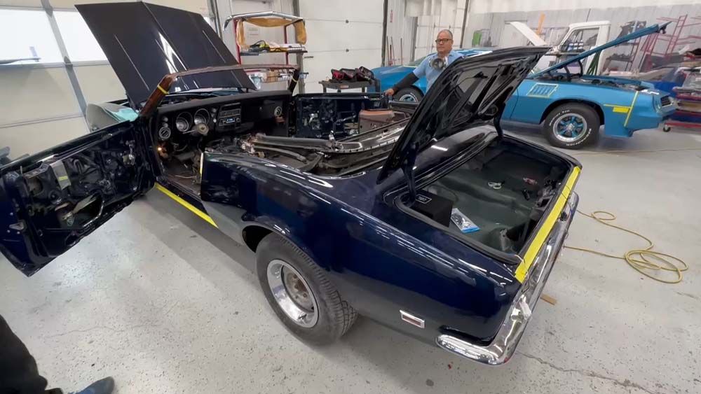 A black car with the hood open is sitting in a garage.