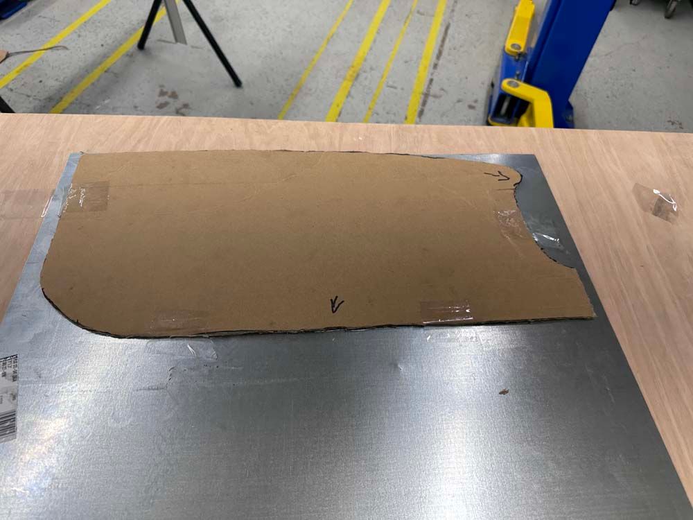 A piece of cardboard is sitting on top of a piece of metal.
