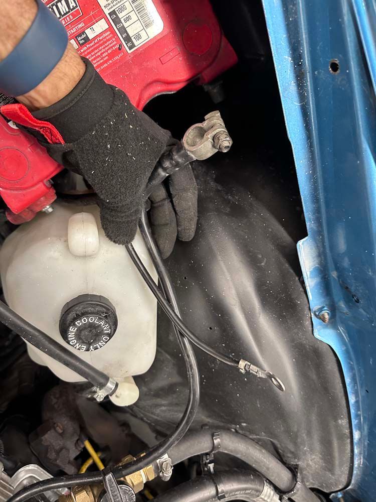 A person wearing gloves is working on a car engine.