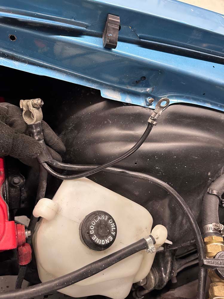 A close up of a car engine with a water tank and a battery.