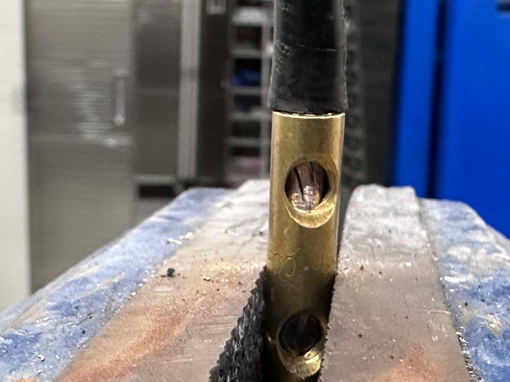 A close up of a brass object in a vise.