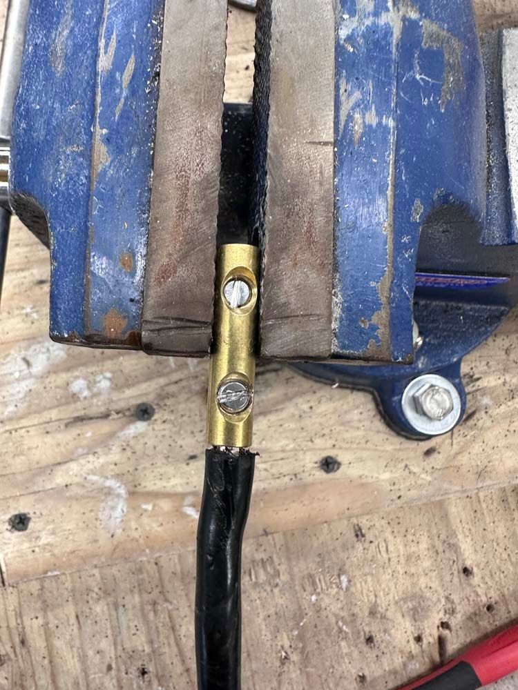 A wire is being held in a vise on a wooden table.