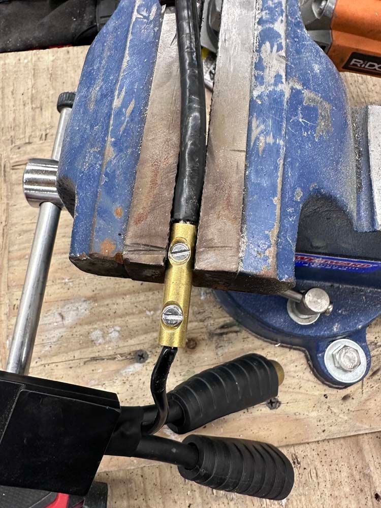A piece of metal is being held in a vise on a wooden table.