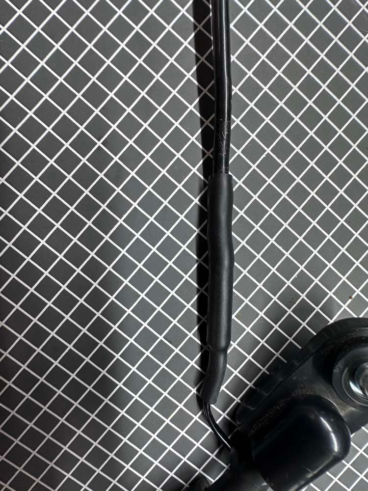 A close up of a black wire on a black and white checkered surface.