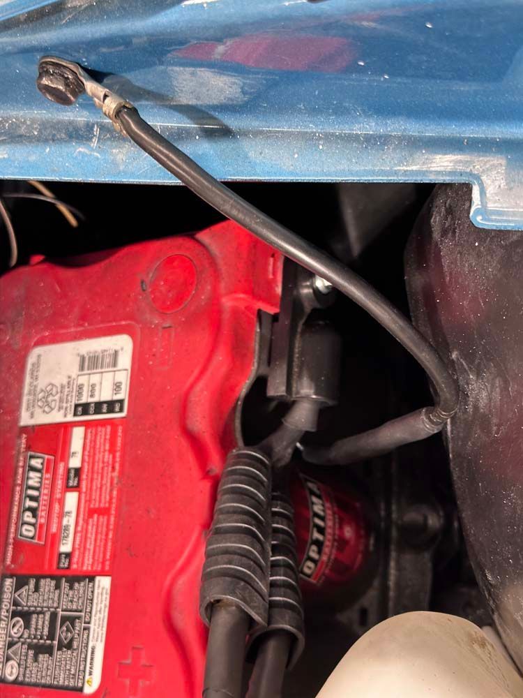 A red optima battery is sitting under the hood of a car.