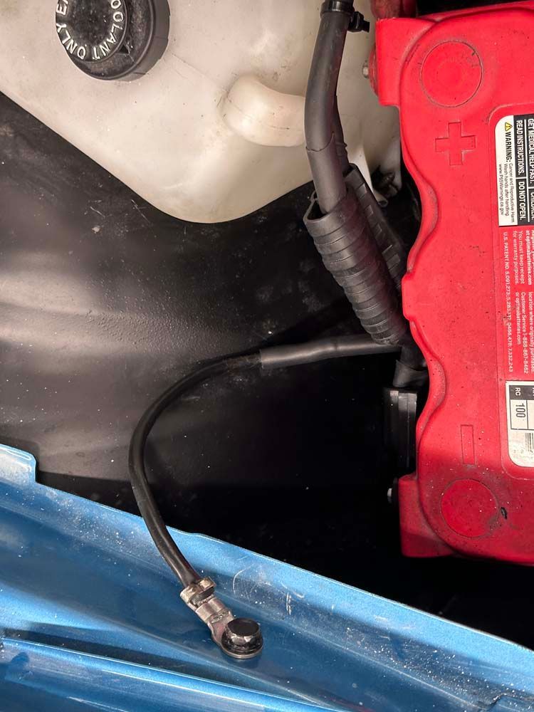 A red battery is sitting under the hood of a car.