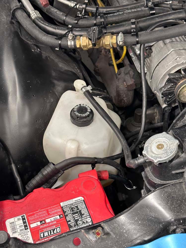 A close up of a car engine with a red battery