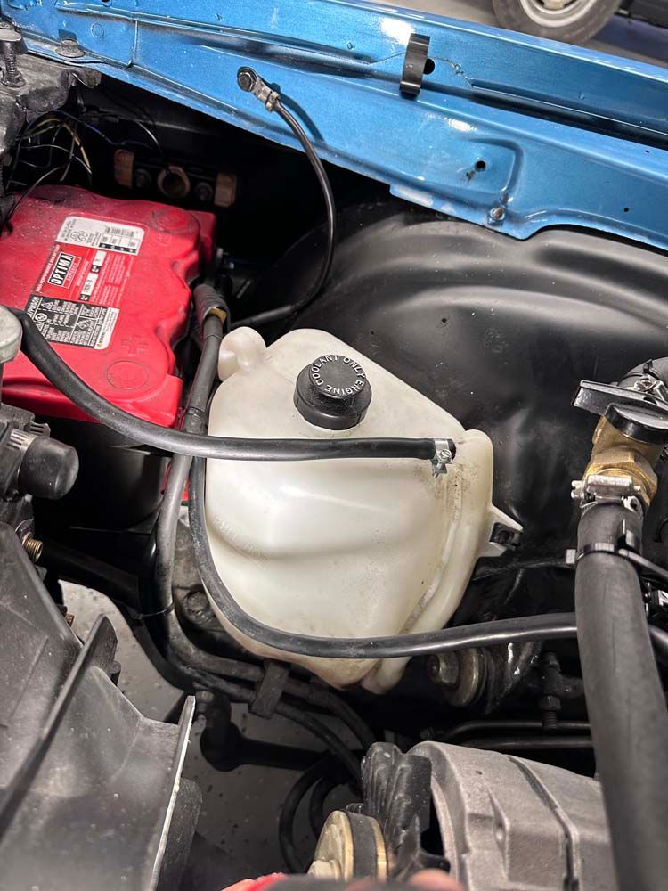 A close up of a car engine with a red battery.