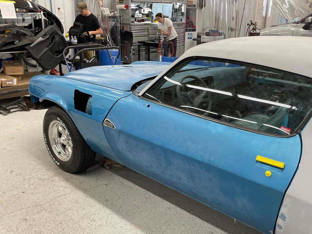 A blue car is being worked on in a garage.