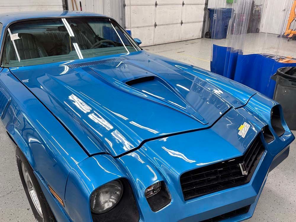 A blue car is parked in front of a garage door.