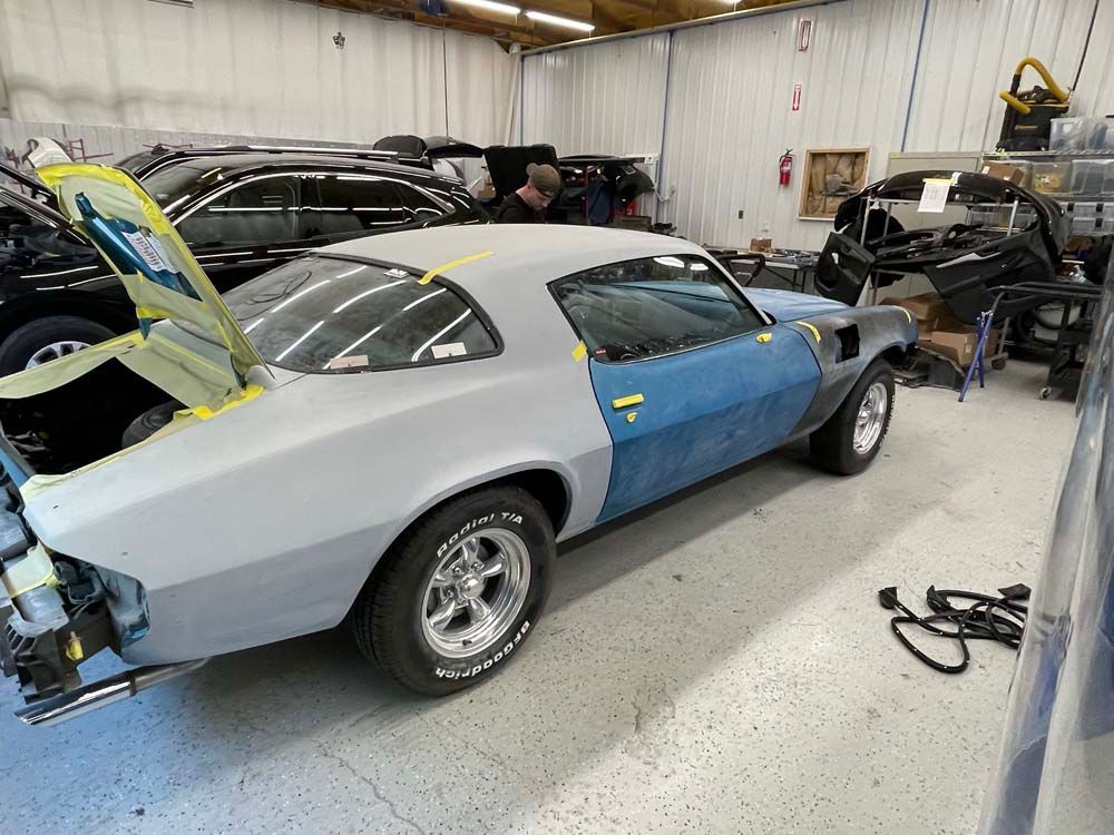 A blue and gray car is being built in a garage.
