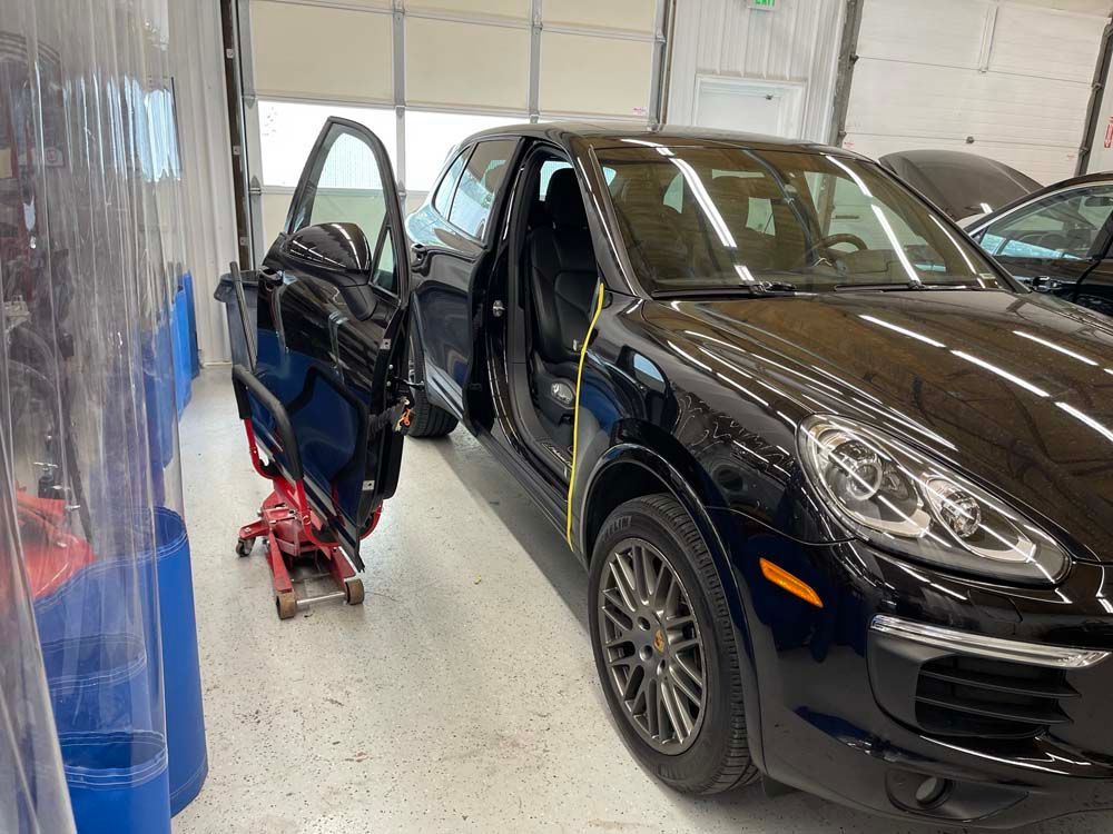 A black car is parked in a garage with its doors open.
