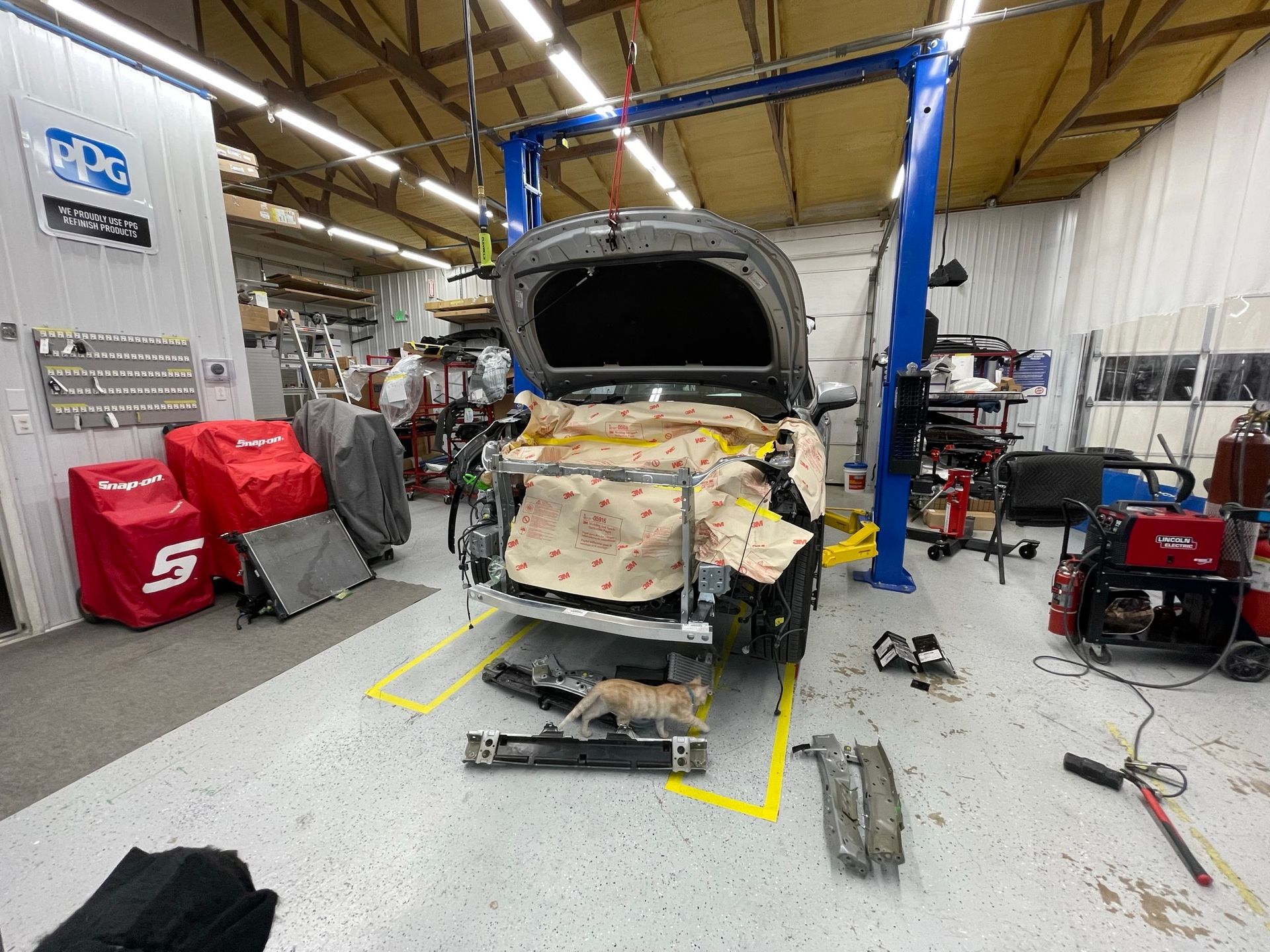 A car is being worked on in a garage with the hood open.