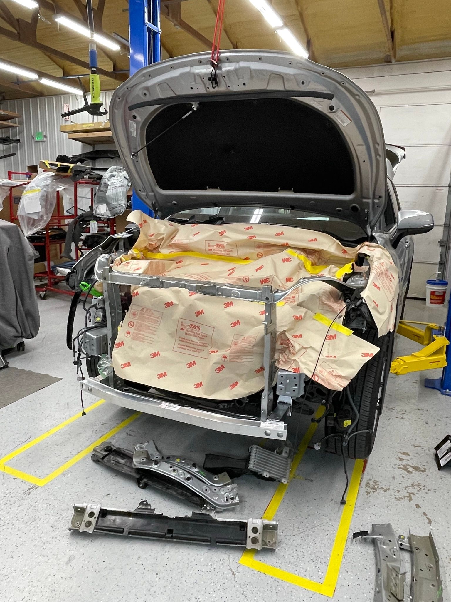 A car is being worked on in a garage with the hood open.