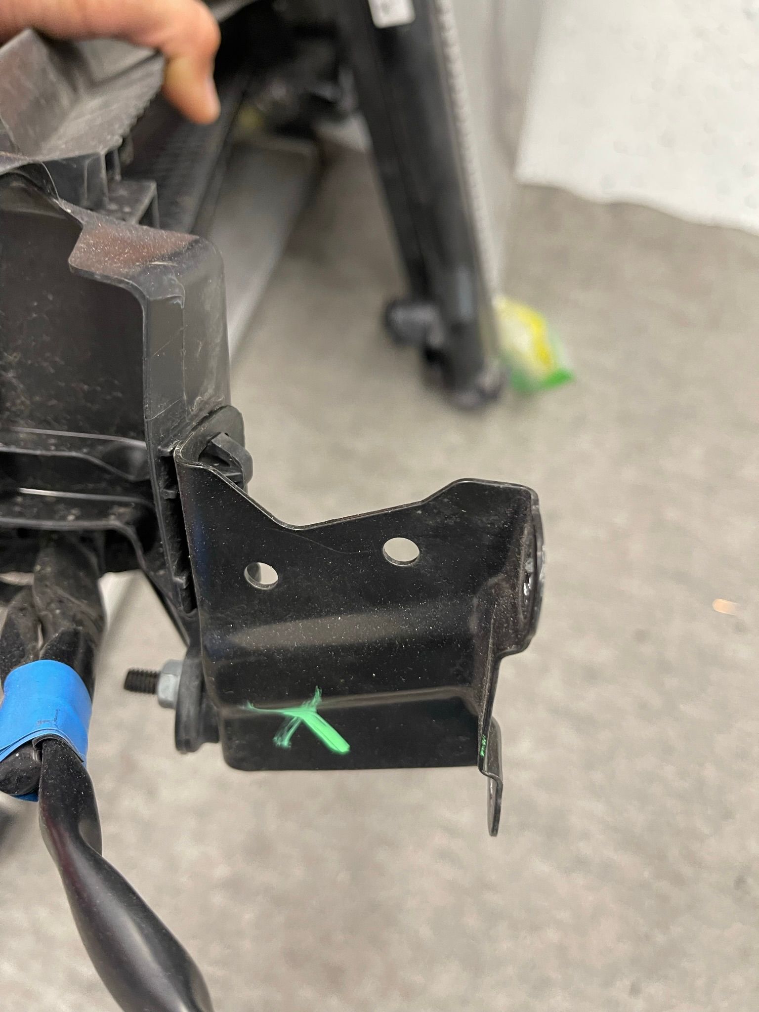 A person is holding a piece of metal with a green x on it.