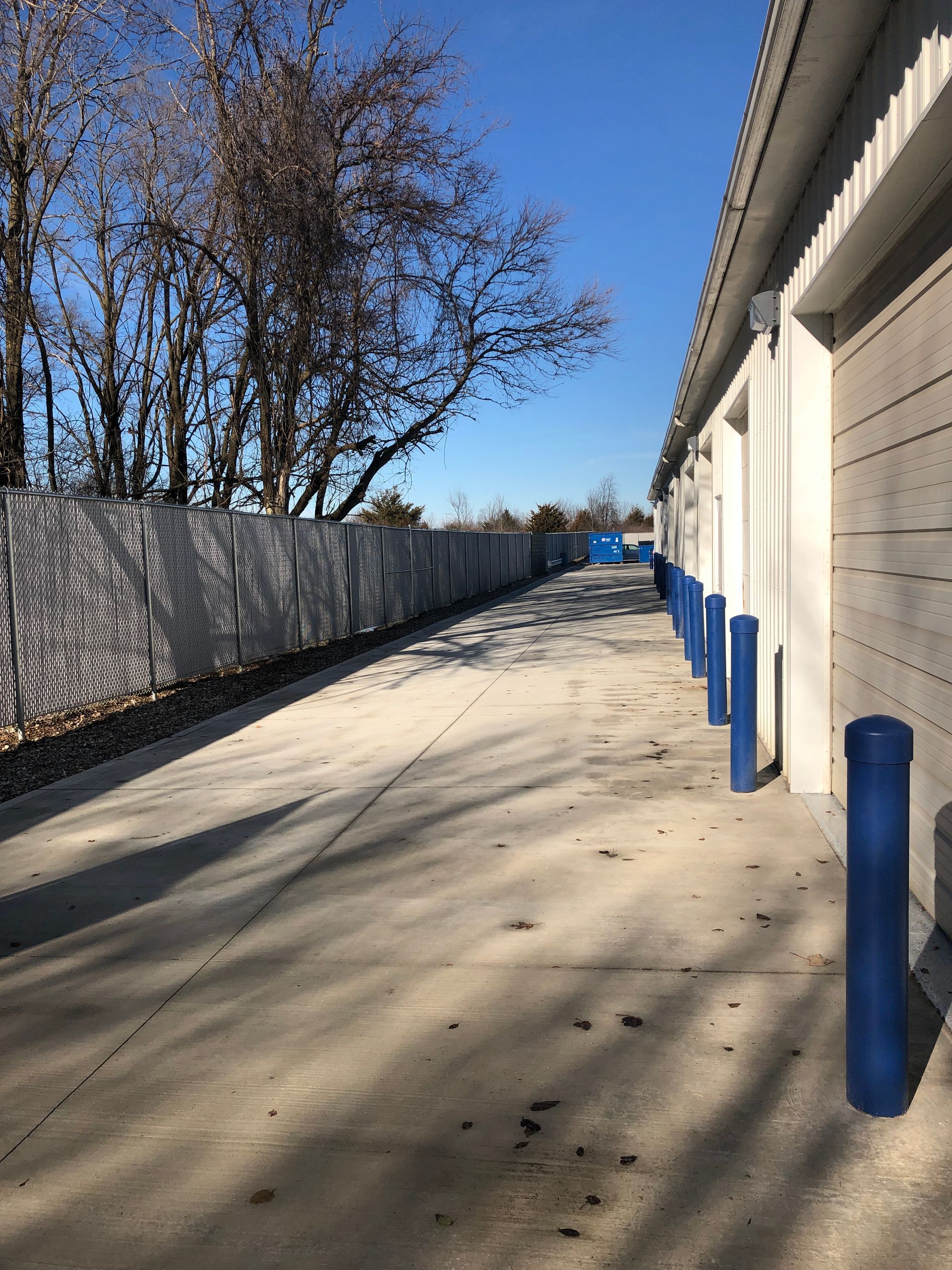 A row of storage units with blue poles on the sidewalk.