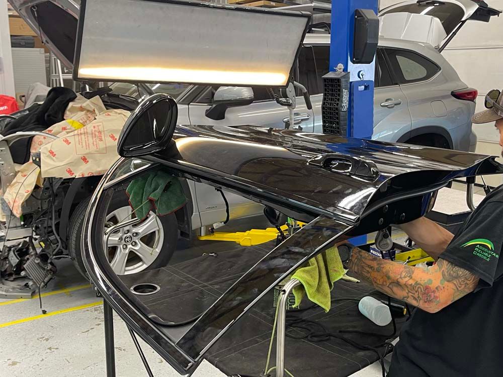 A man is working on a car door in a garage.