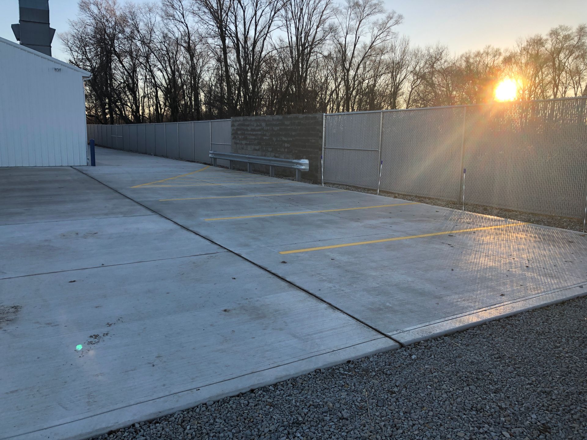 A parking lot with a fence and trees in the background