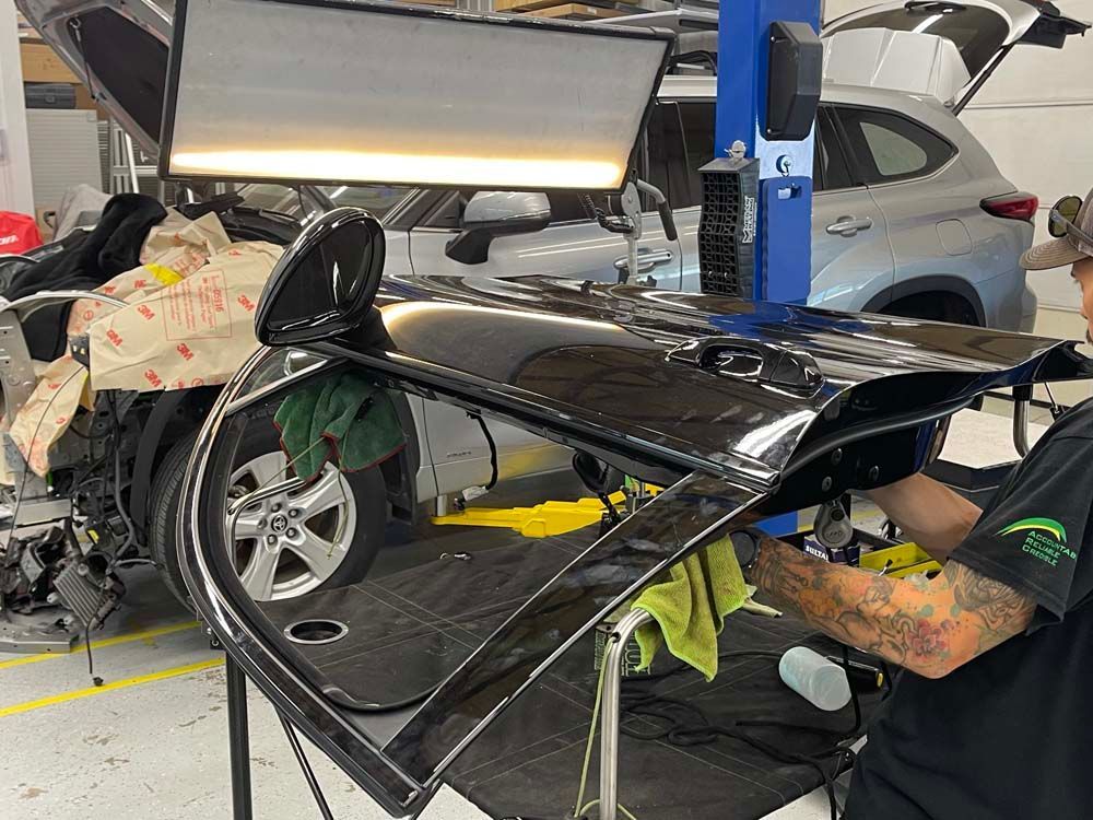 A man is working on a car door in a garage.