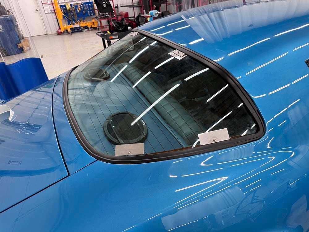 A close up of a blue car 's windshield in a garage
