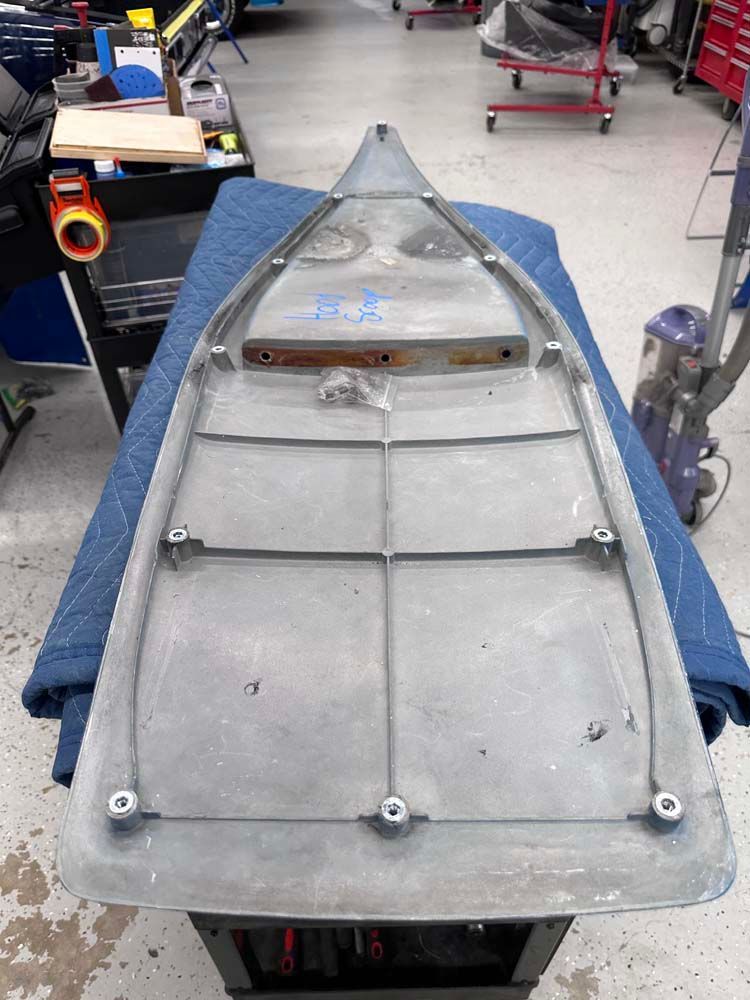 A boat is sitting on top of a table in a garage.