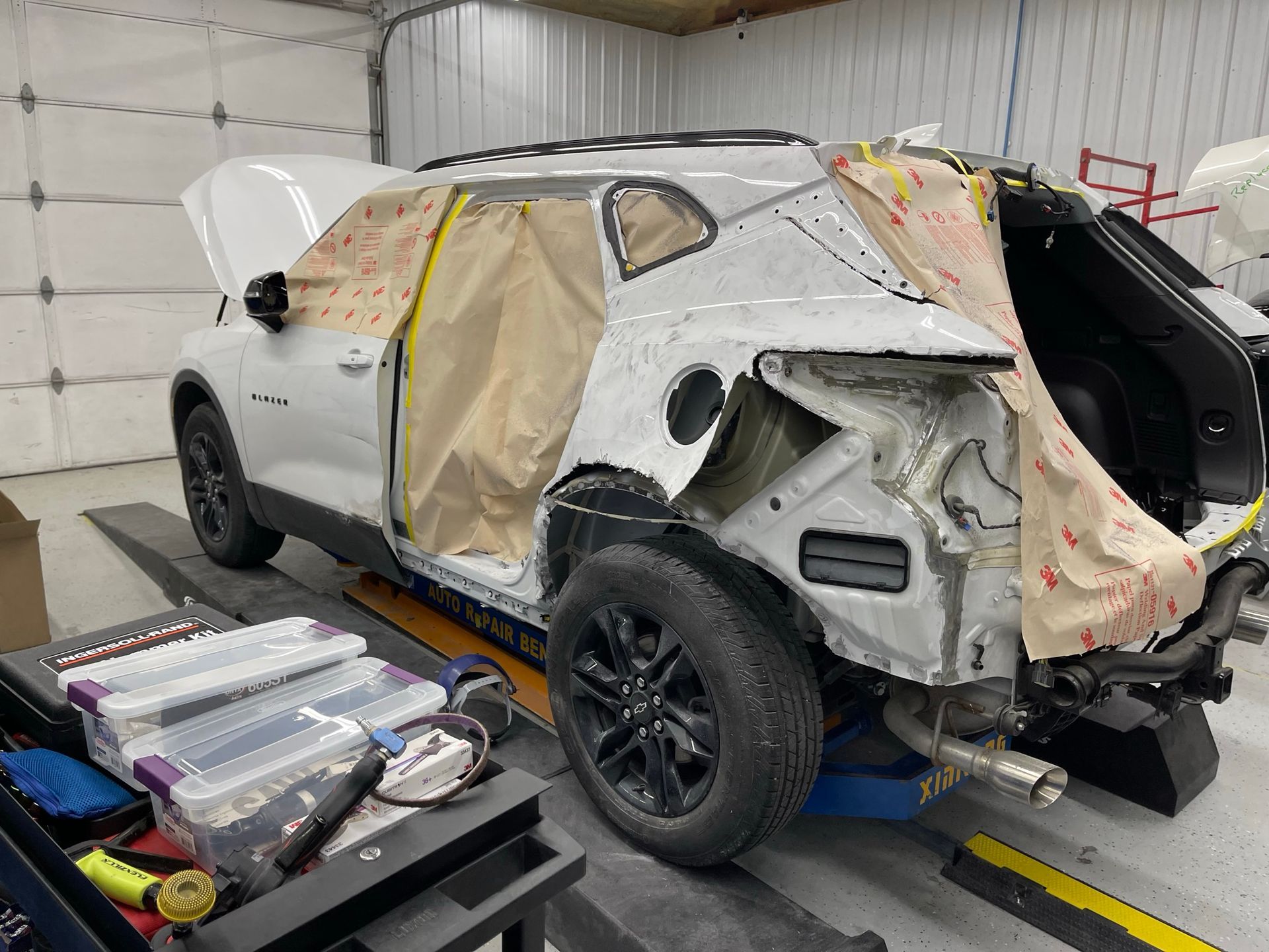 A white suv is sitting on a lift in a garage.