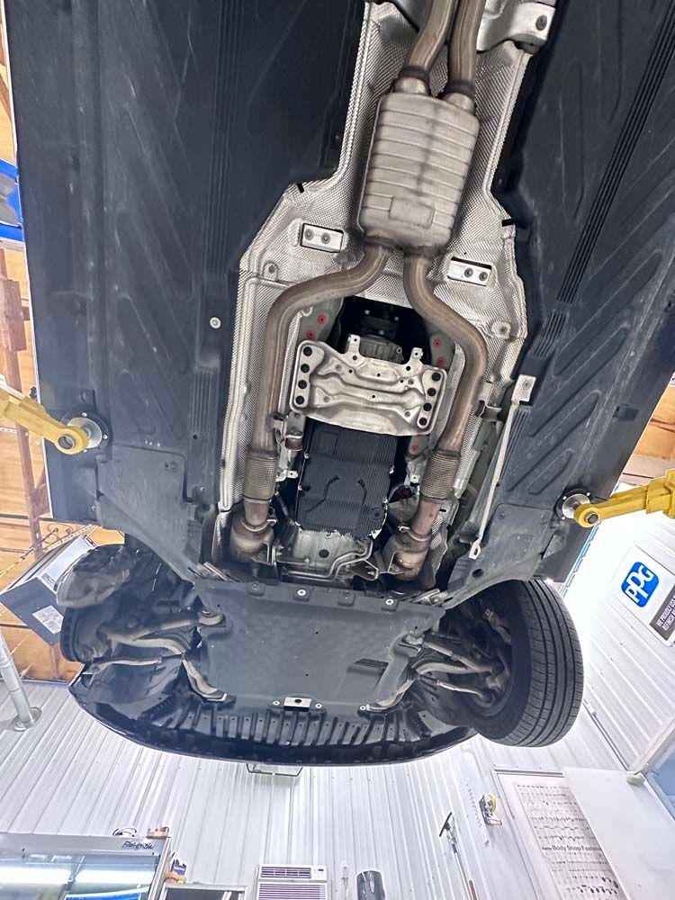 The underside of a car is shown in a garage.