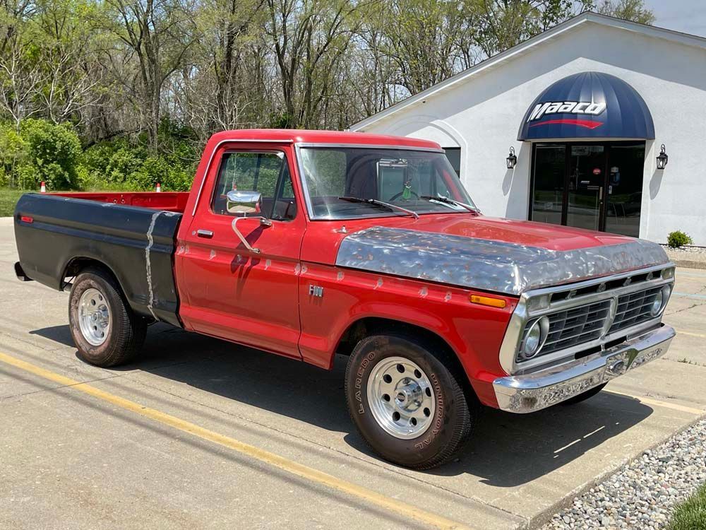 A red and black pickup truck is parked in front of a building.
