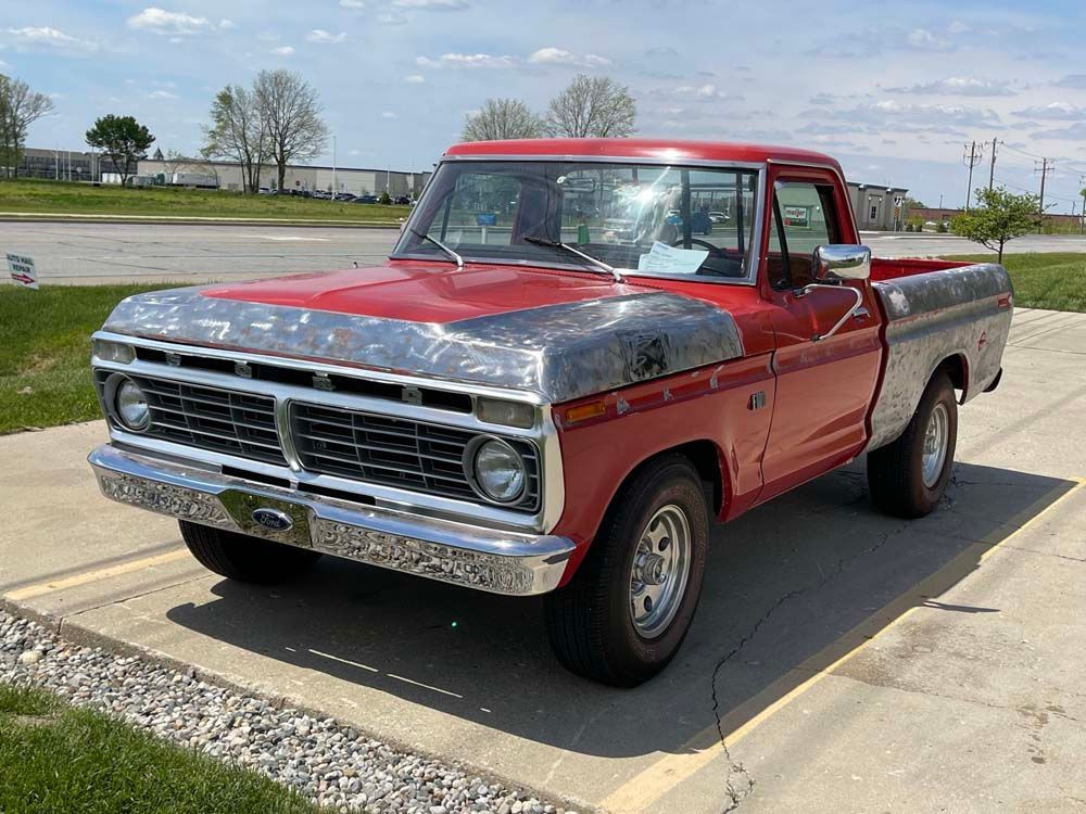 A red ford truck is parked in a parking lot.