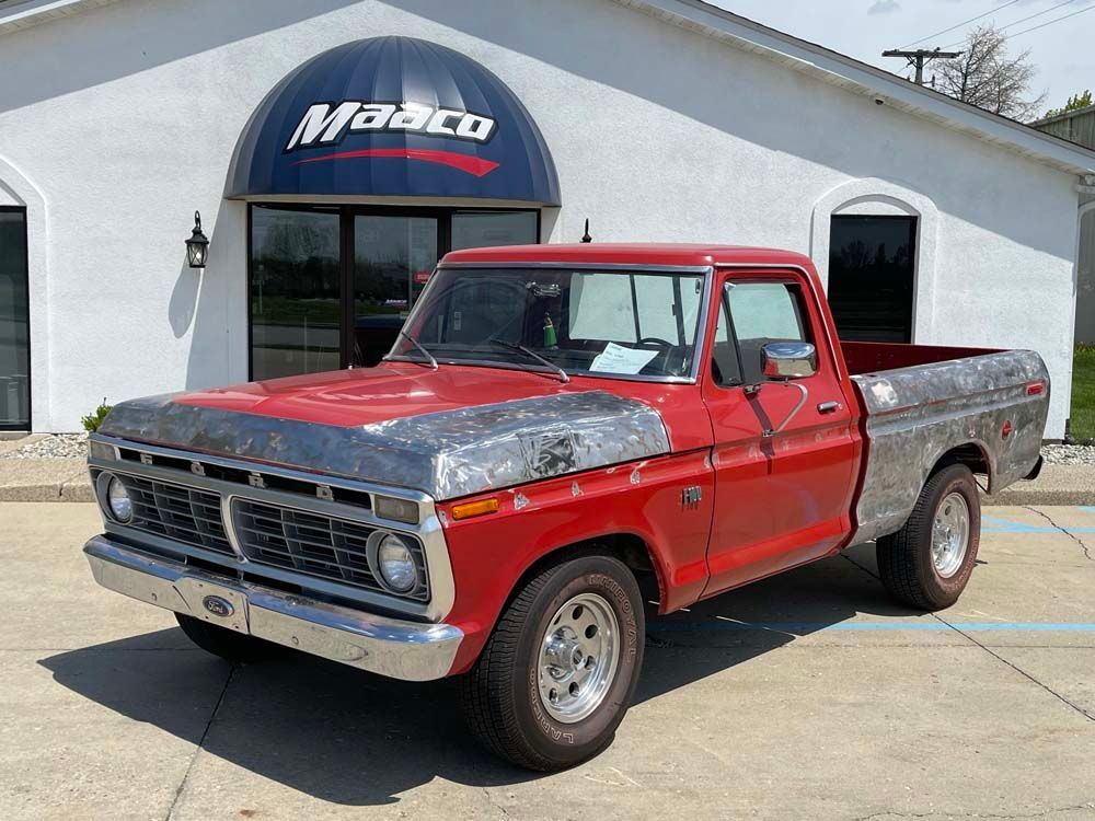 A red pickup truck is parked in front of a white building.