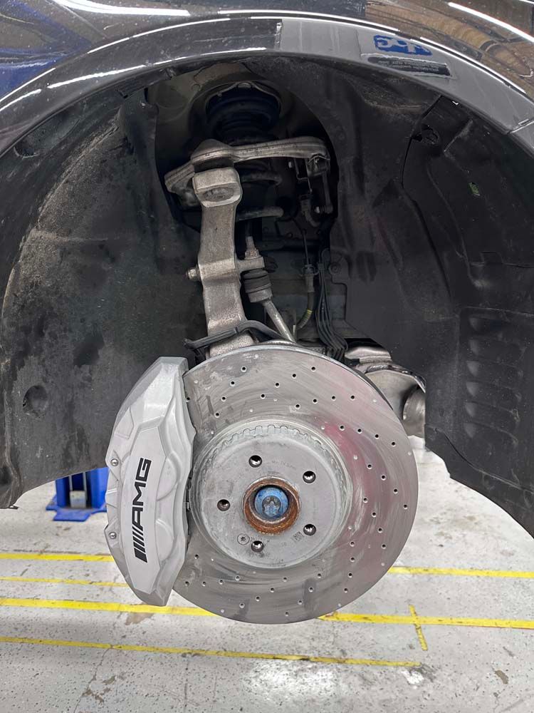 A close up of a brake disc on a car in a garage.