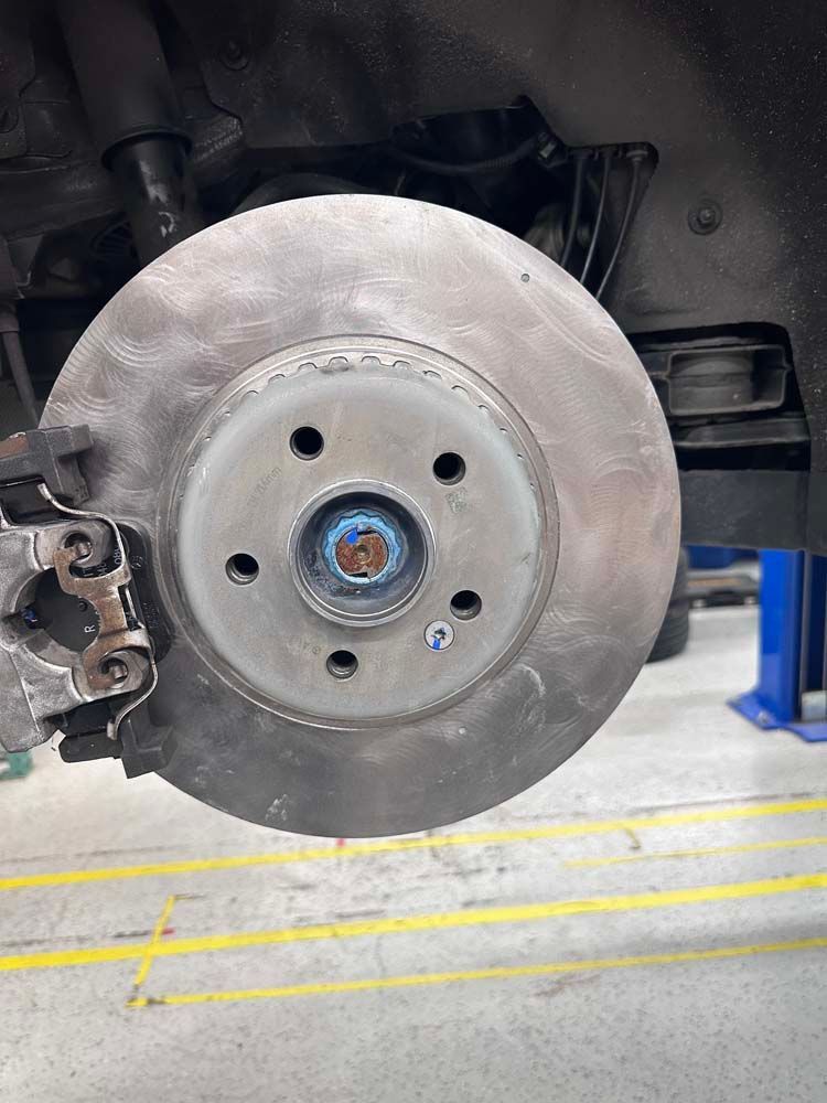 A close up of a brake disc on a car in a garage.