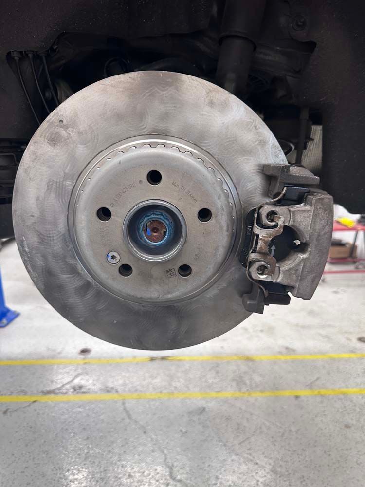 A close up of a brake disc on a car in a garage.