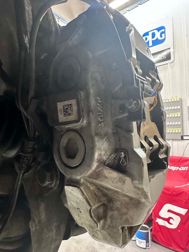 A close up of a brake caliper on a car in a garage.