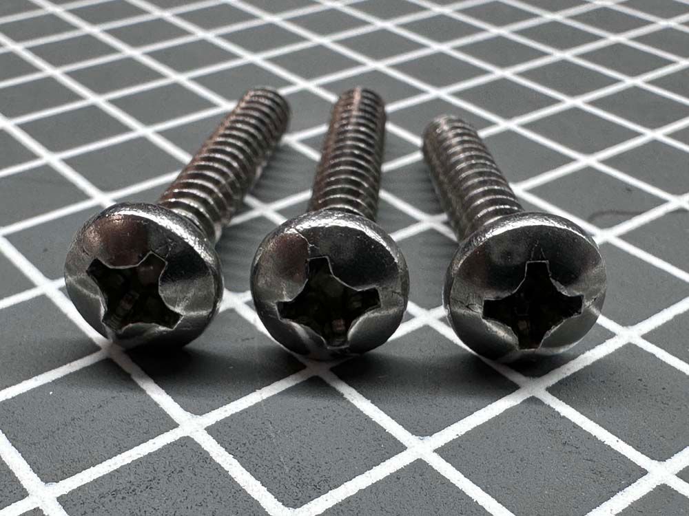 Three screws are sitting on a checkered surface