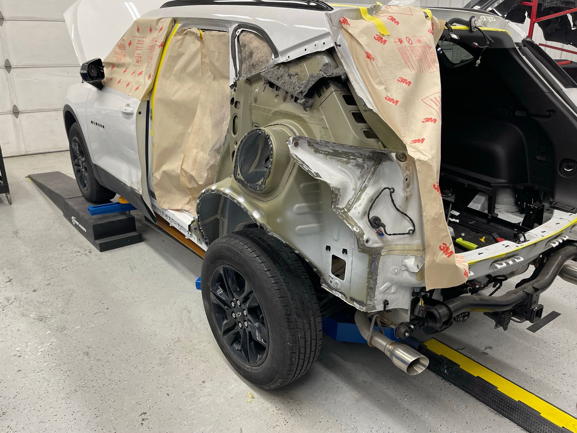 A white car is being dismantled in a garage.