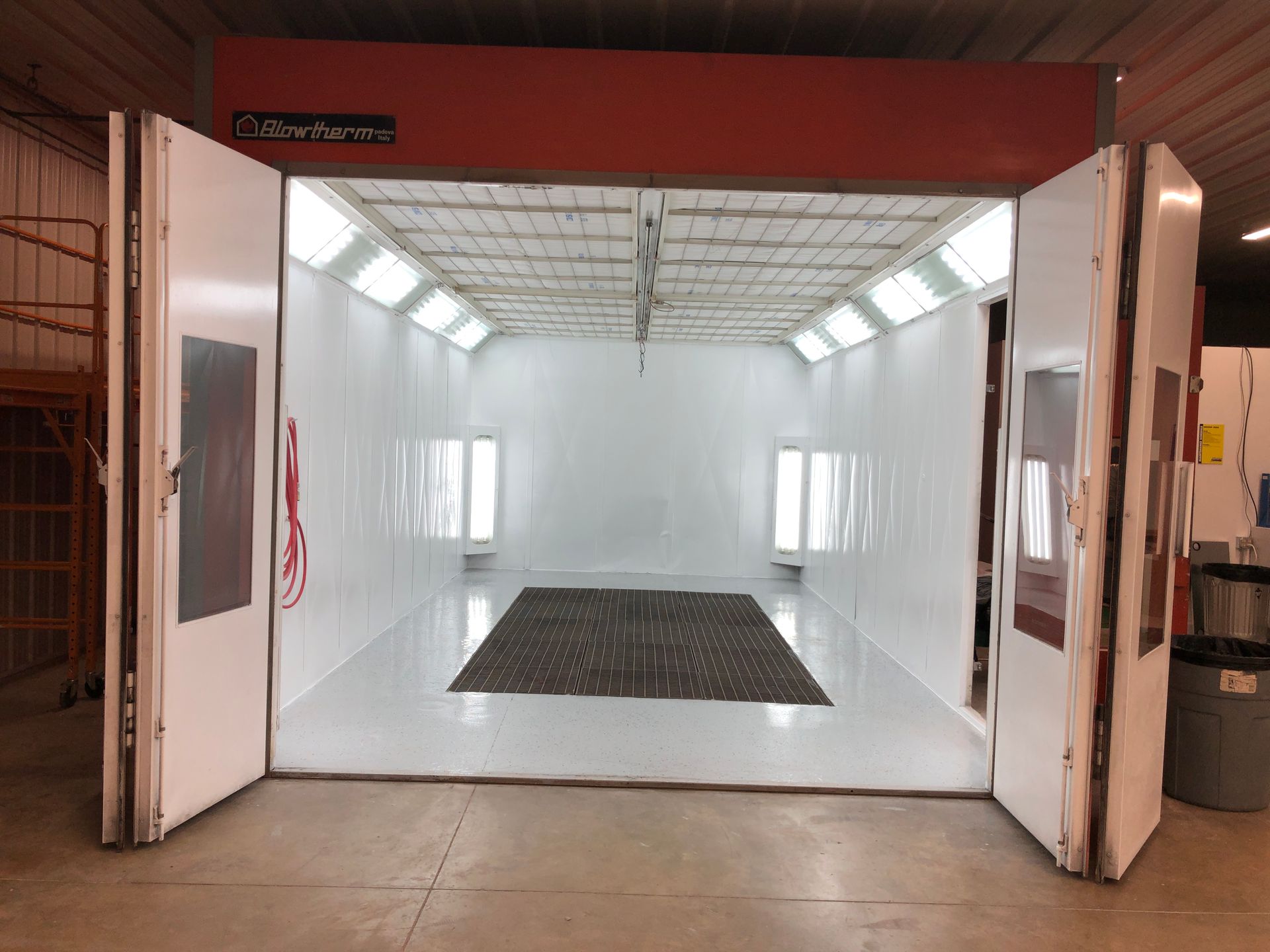 An empty paint booth with the doors open in a garage