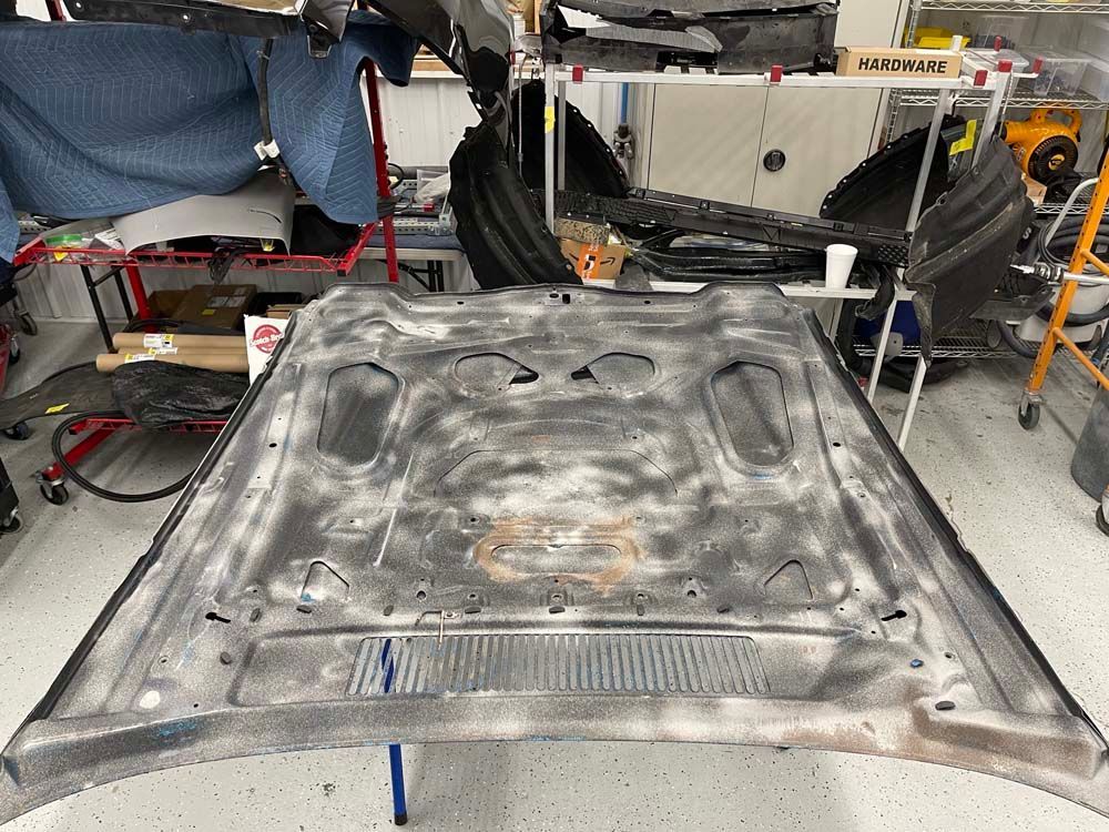 The hood of a car is sitting on a table in a garage.