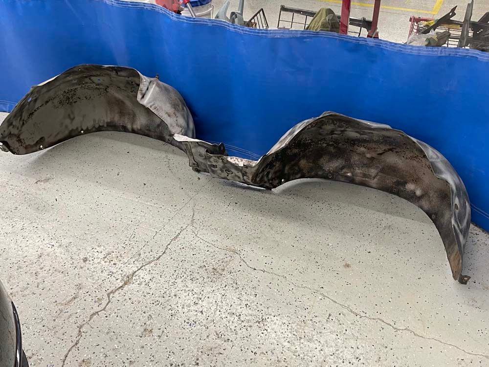 A pair of fender liners are sitting on a concrete floor next to a blue wall.