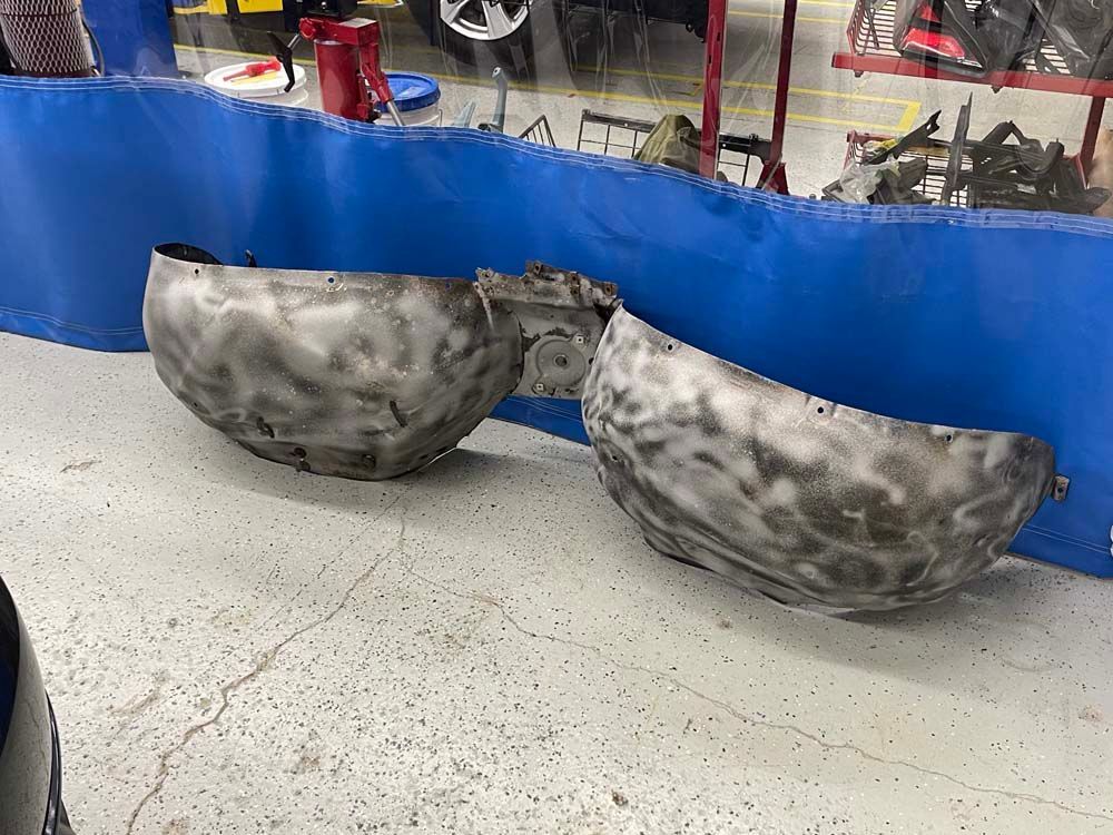 Two metal bowls are sitting next to each other on the floor in a garage.