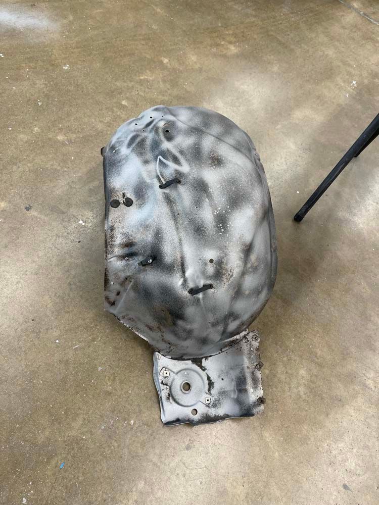 A piece of metal is sitting on the ground next to a chair.