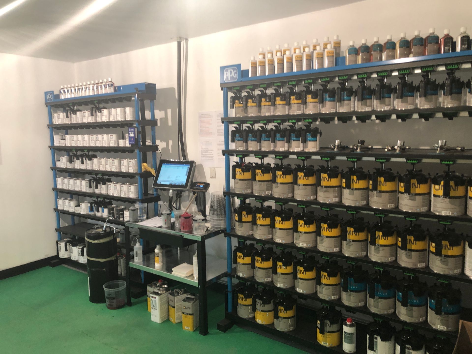 A room filled with lots of bottles of paint and a computer.