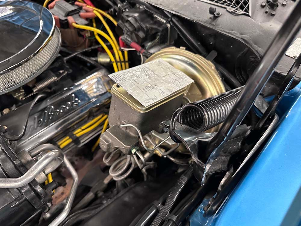 A close up of a blue car engine with the hood open.