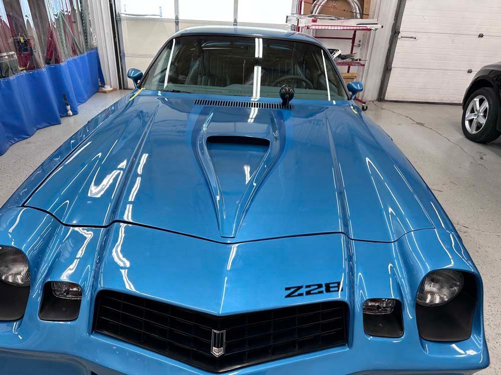 A blue chevrolet camaro is parked in a garage.