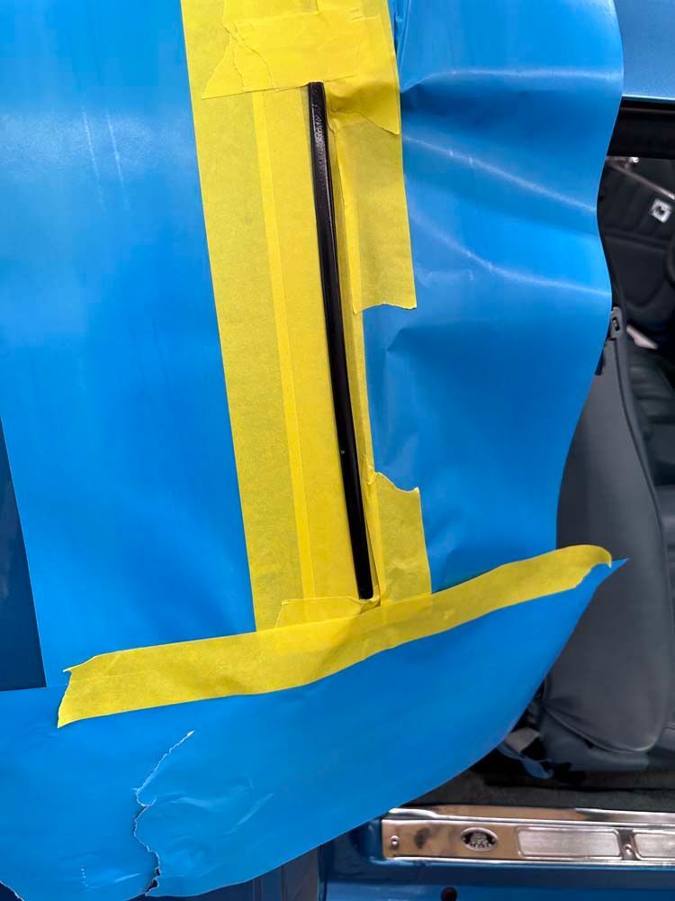 A blue and yellow piece of tape is covering a hole in a car door.