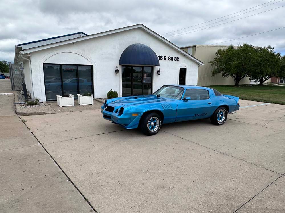 A blue car is parked in front of a white building.