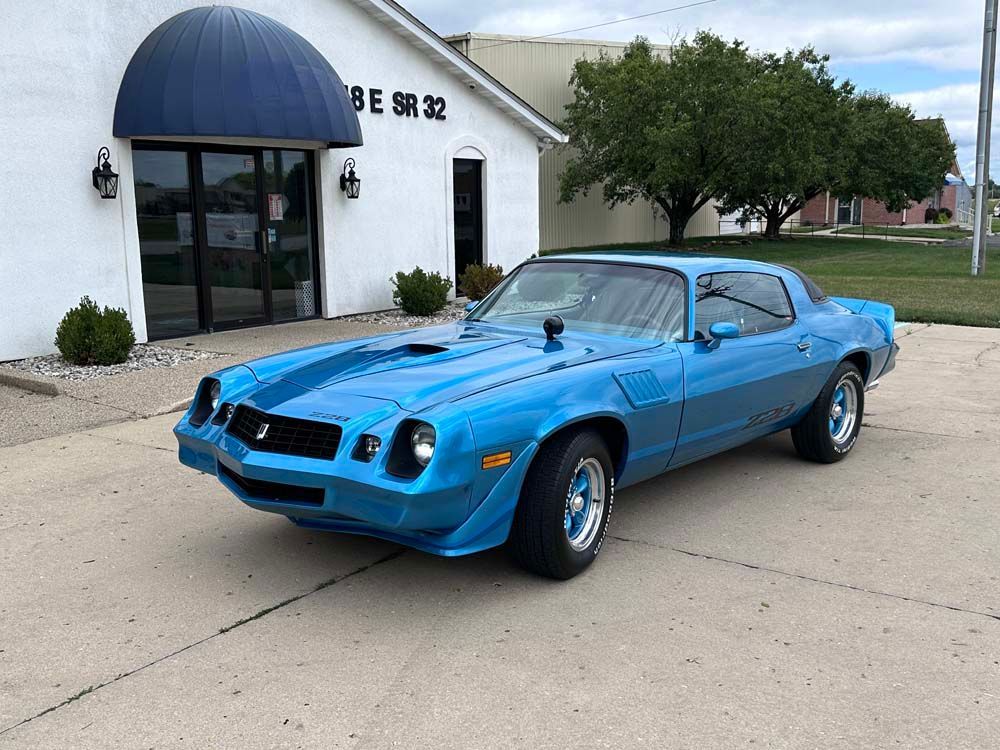 A blue car is parked in front of a white building.