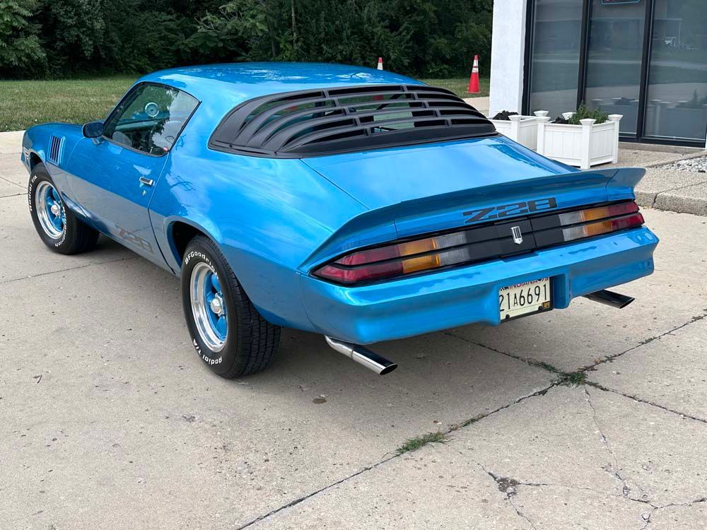 A blue car is parked in a parking lot in front of a building.